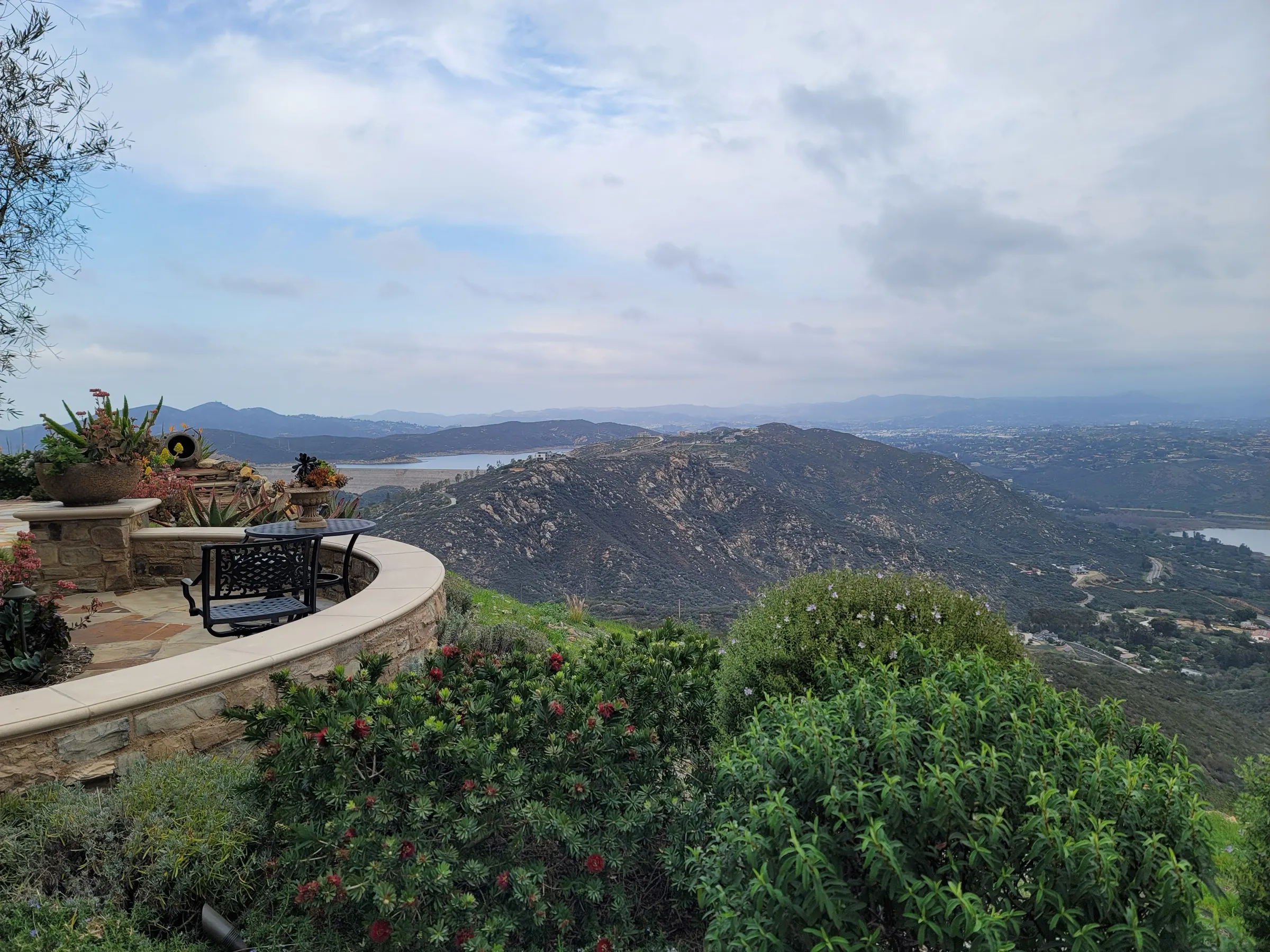 Planted hillside landscape beside a curved stone terrace and outdoor seating